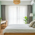 A calm green bedroom with soft walls, plants, and light wood